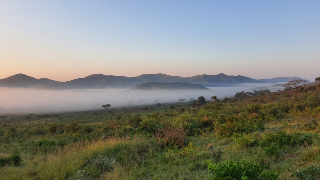 Ein Tal liegt im Nebel, während die Sonne aufgeht
