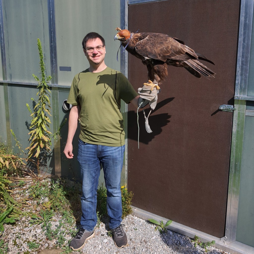 Sebastian hat den Steinadler Bruno mit seiner Haube auf der Hand (© Cornelia Hebrank, 2024)